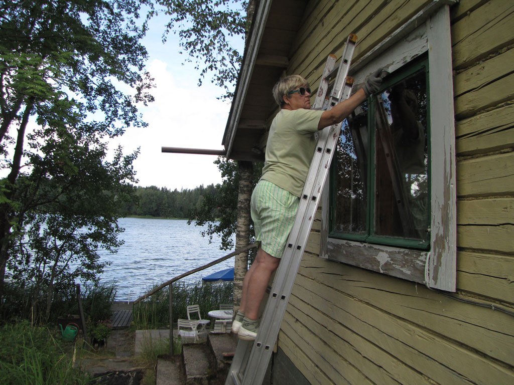Merja Paulin maalaa Kivirannan saunarakennuksen ikkunanpieliä kesällä 2010.